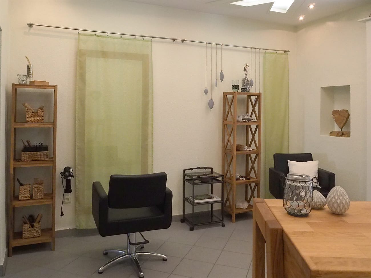 Bedienplatz im Salon mit Holzregalen und grünen Vorhängen
